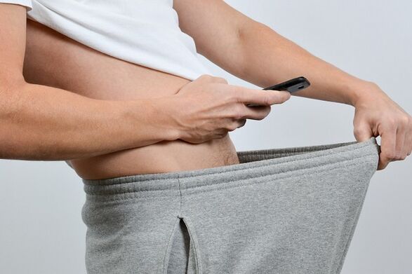 мушкарац гледа низ панталоне у увећани пенис